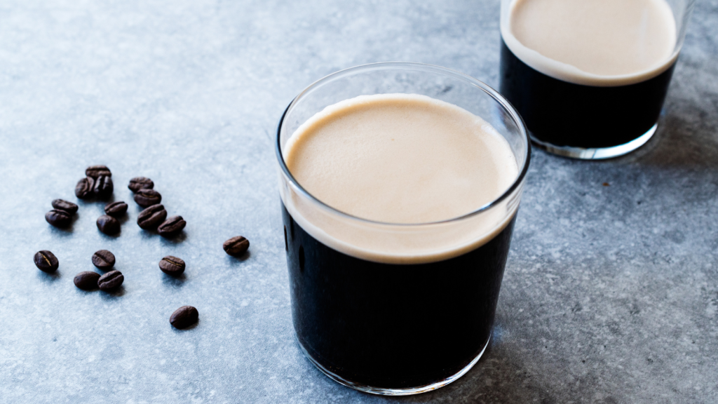 Frothy cold brew on the bar with roasted coffee beans