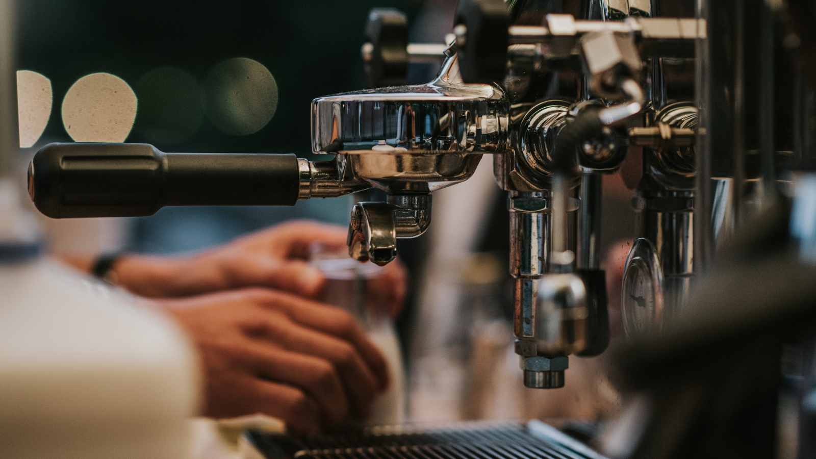 Espresso machine with hands making drinks on the bar at coffee shop