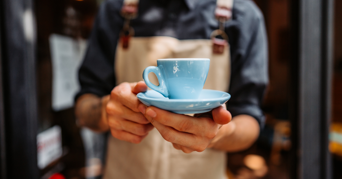 Barista Serving blue demitasse cup of coffee
